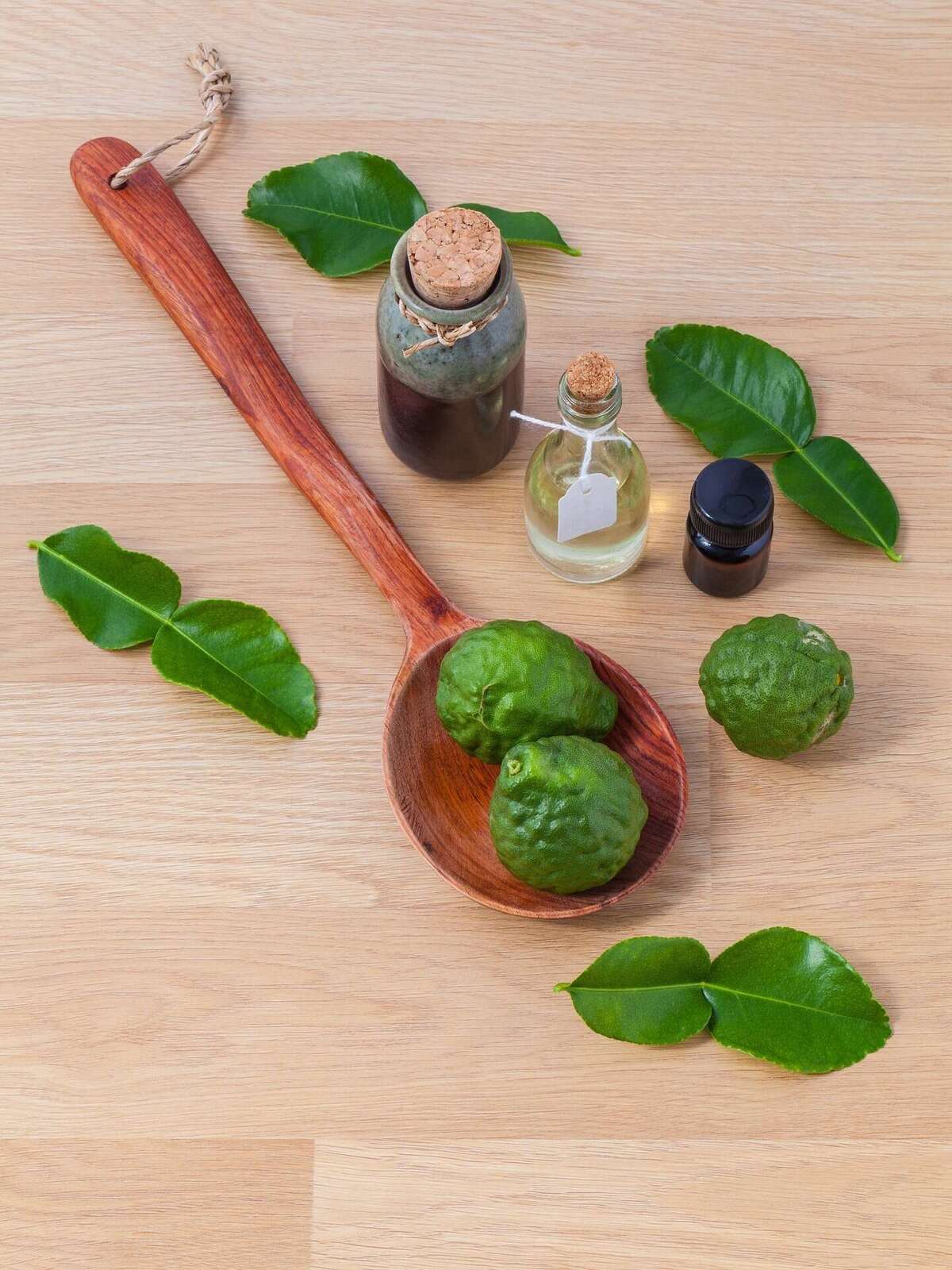 Cuillère en bois garnie de plantes aromatiques, entourée de petits flacons
